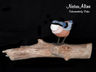 Handgefilzter Vogel in Blau, Rostbraun und Weiss auf einem Schwemmholzast.